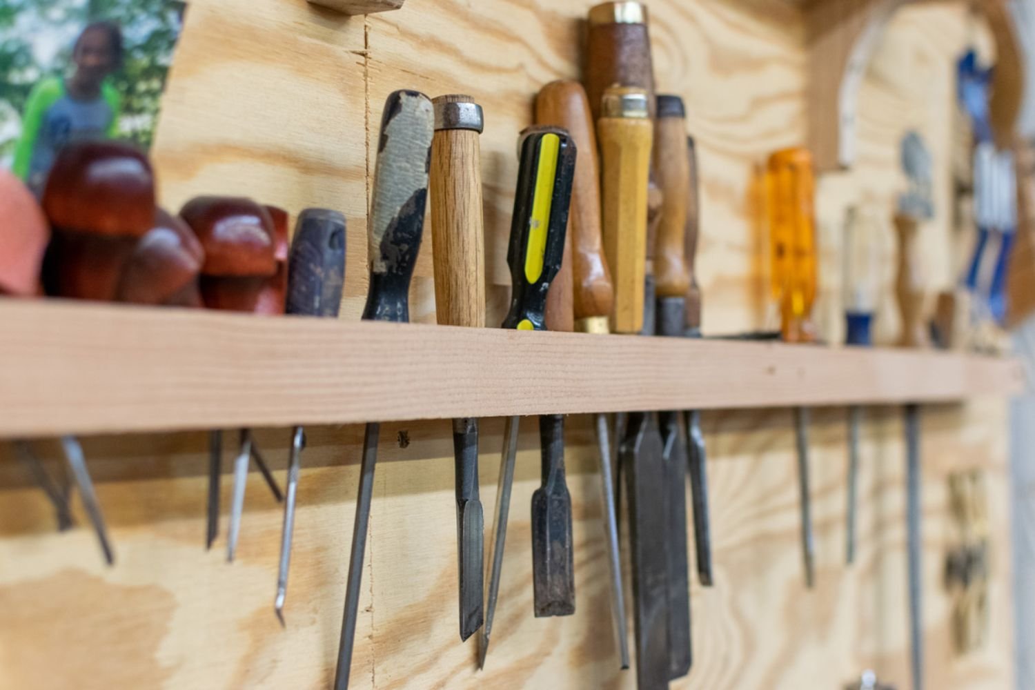 A wooden shelf displaying various tools, including hammers, wrenches, and screwdrivers, organized neatly.