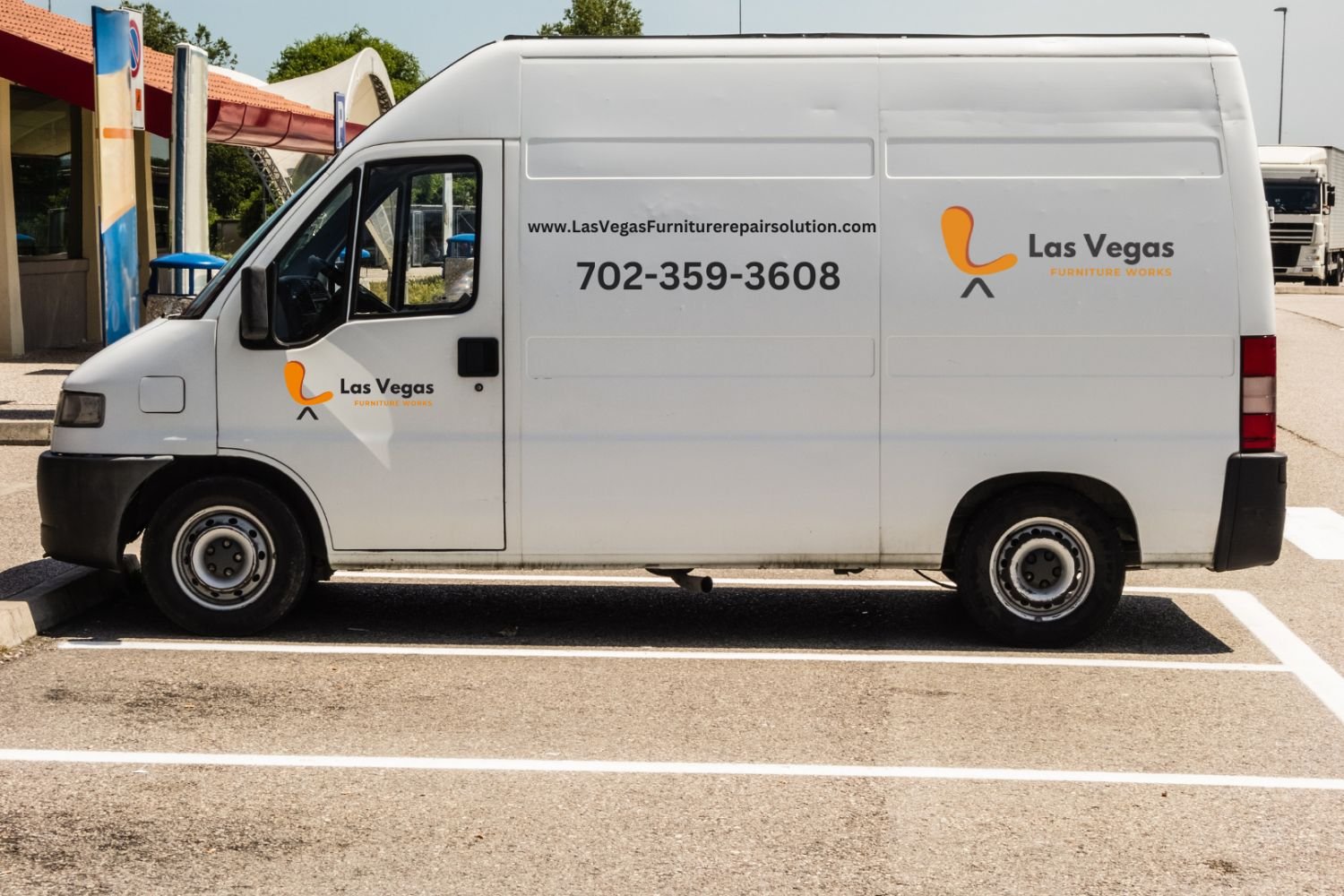 Side view of a white delivery van with "Las Vegas" branding and contact number parked in a parking lot.