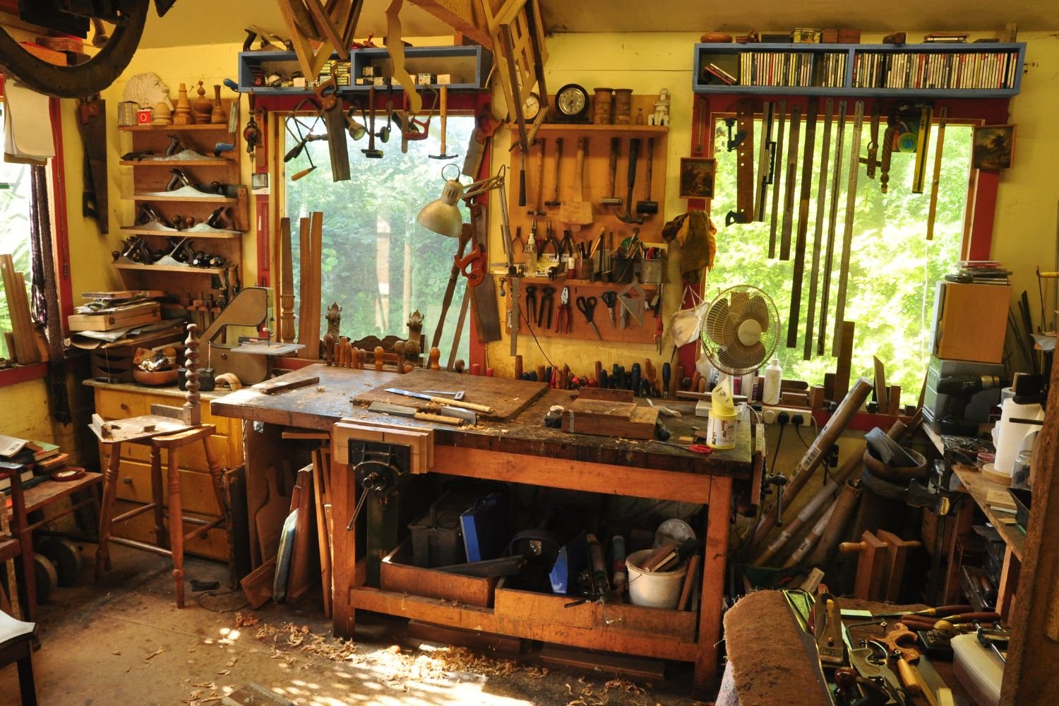 A woodworking shop filled with various tools, including saws, chisels, and workbenches, showcasing a craftsman's workspace.